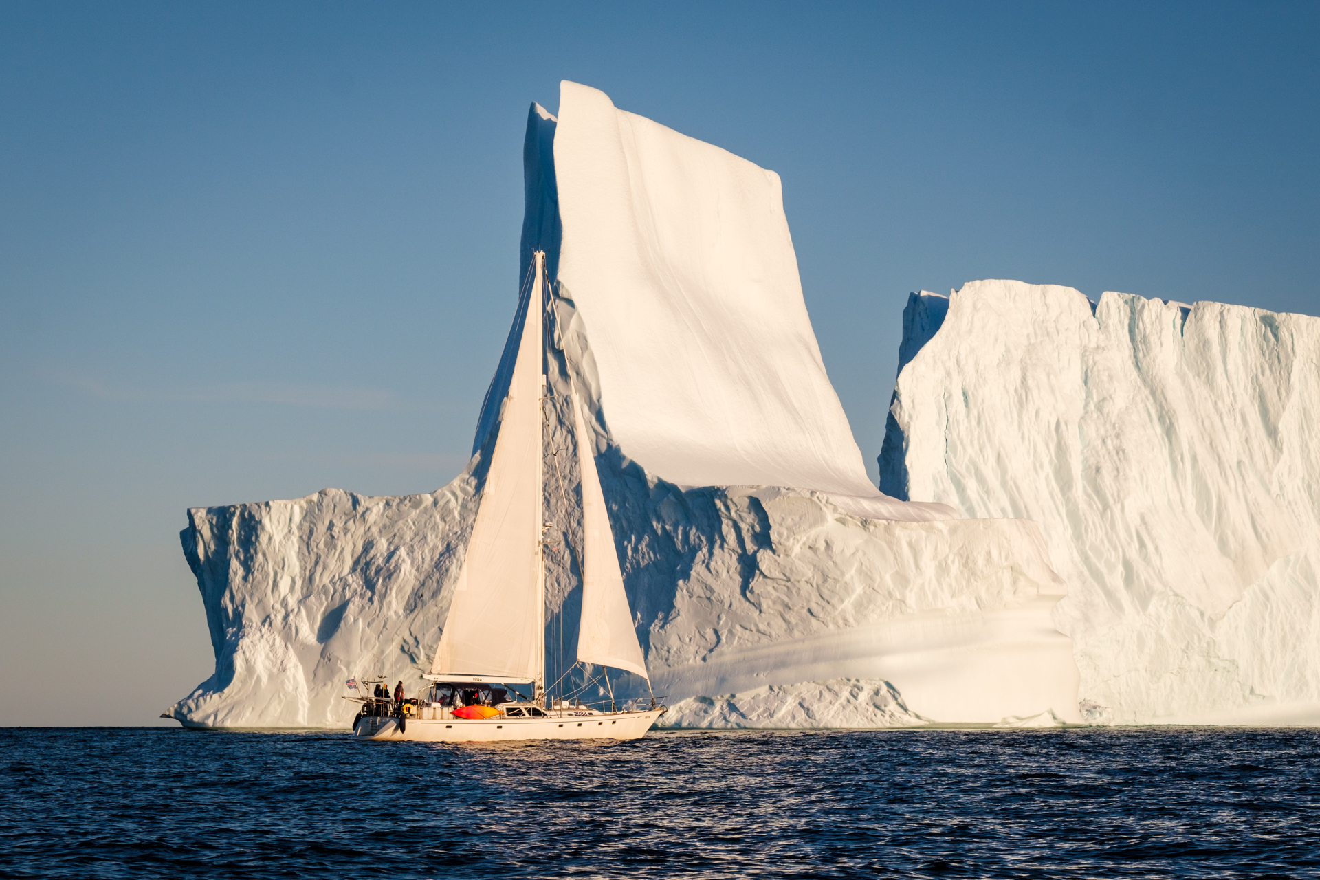 A sailing yacht in front of a huge iceberg in Greenland's Scoresbysund.